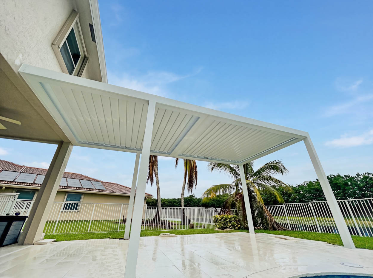Adjustable louvered roof panels allowing airflow and rain protection, ideal for poolside patios in South Florida.
