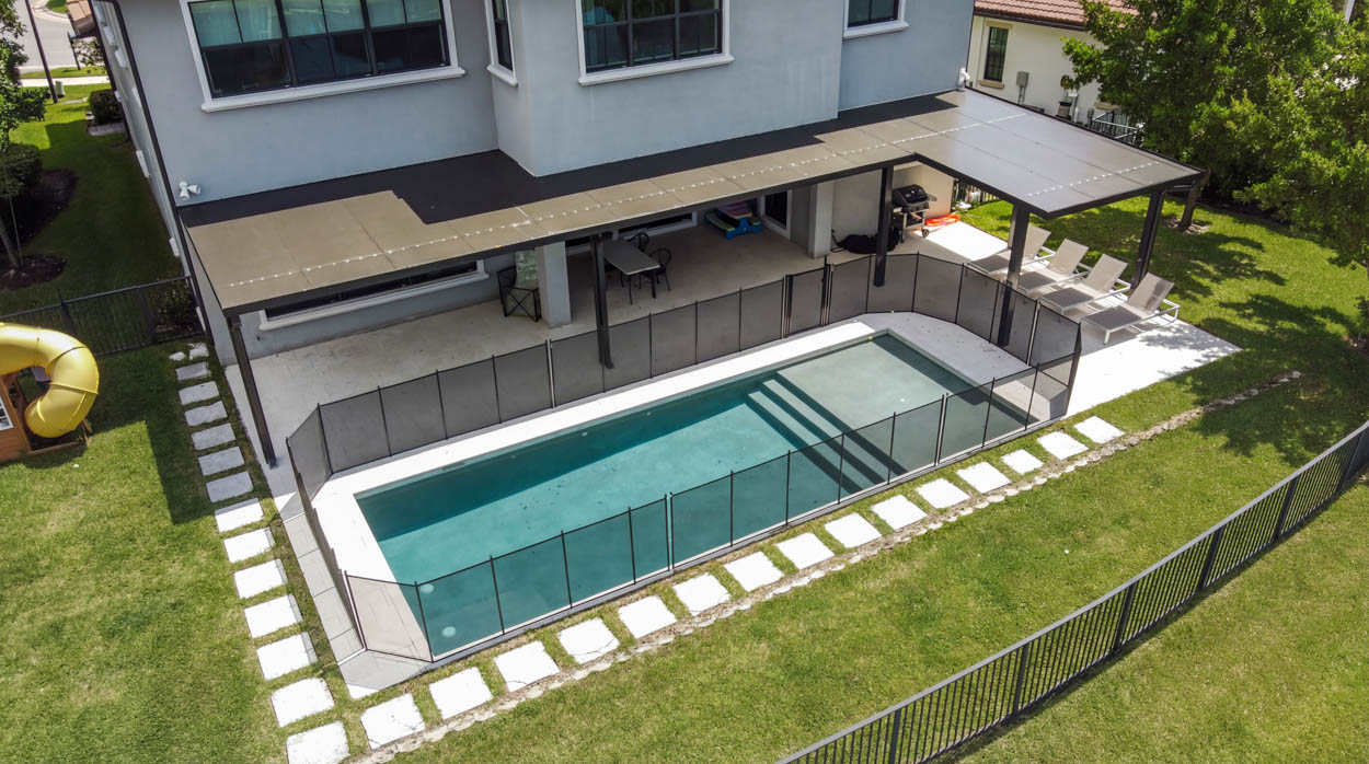 Custom inground pool installation with pergola and safety fencing, built by licensed Florida pool builders.