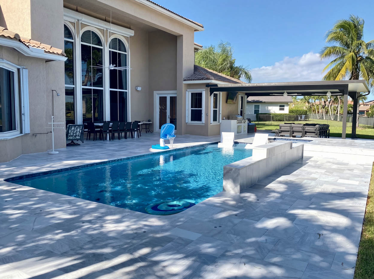 Contemporary pool installation with raised spa and outdoor lounge space, designed for luxury Florida backyard living.