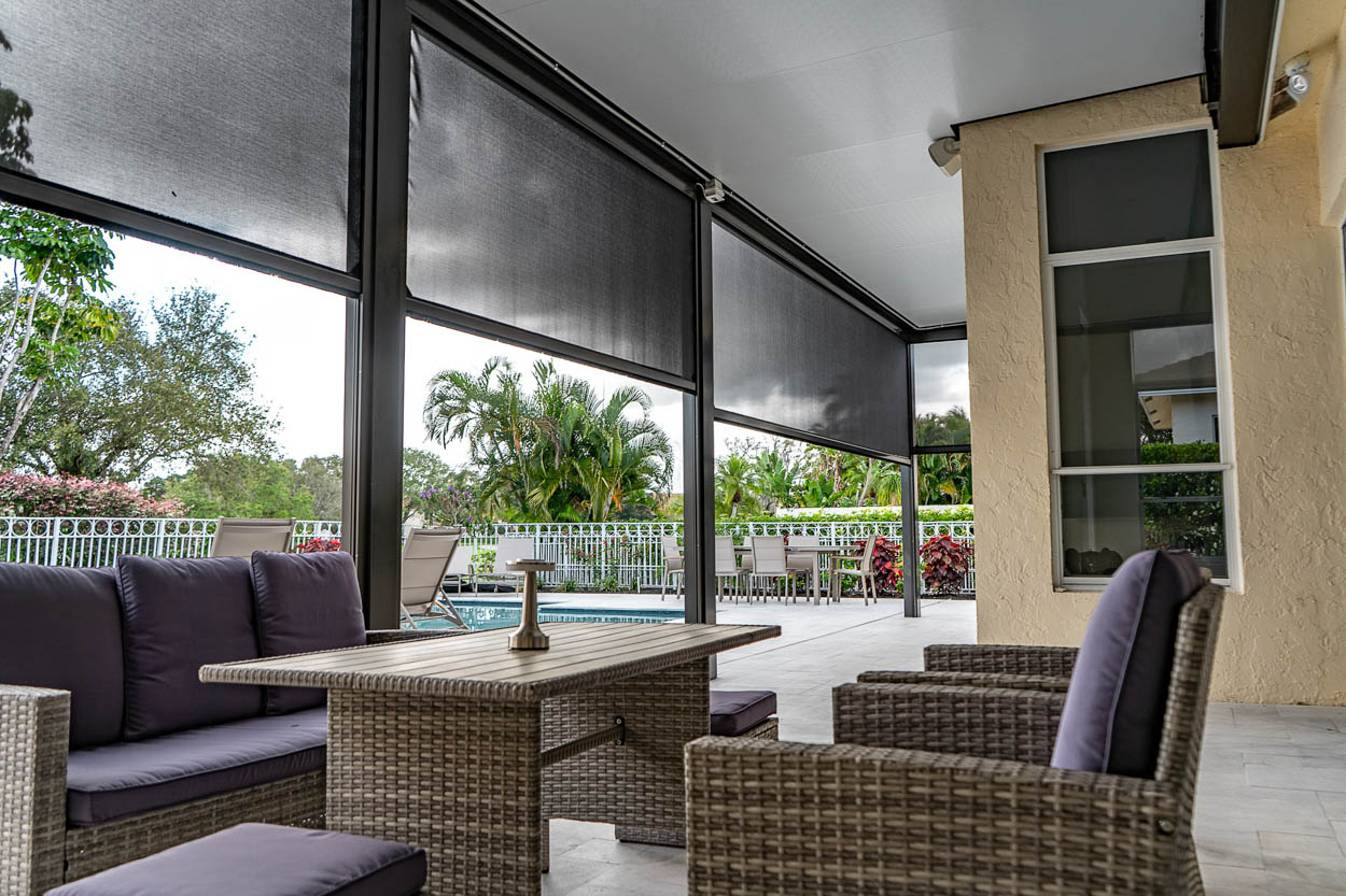 Modern residential patio featuring a motorized retractable screen system designed to protect outdoor living areas from insects, sun, and weather. Ideal solution for pool patios in South Florida homes.