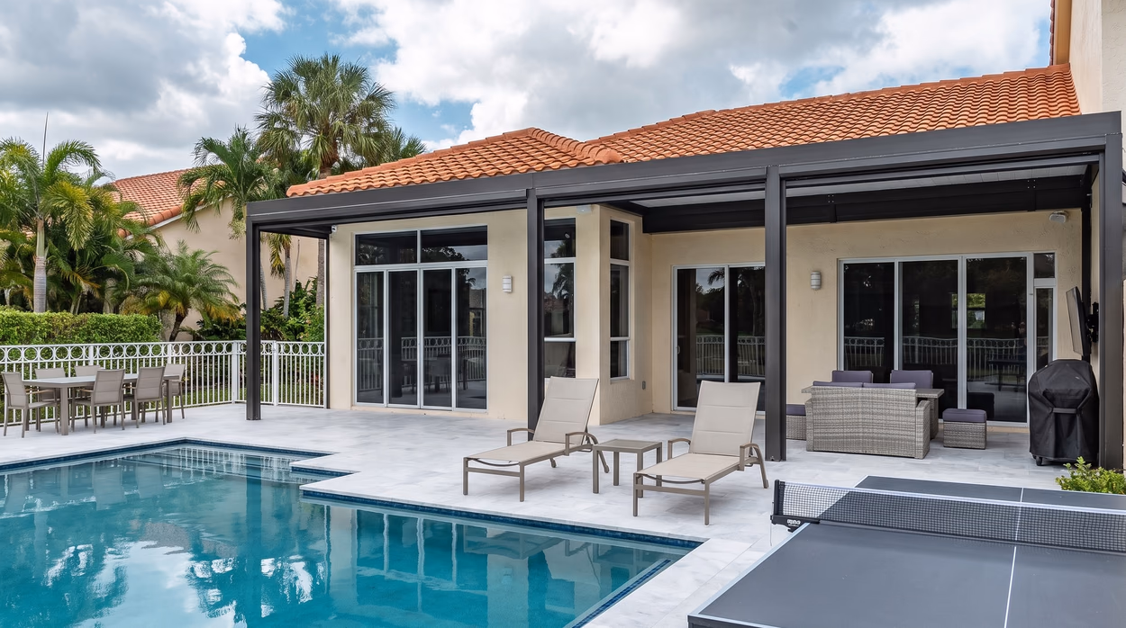 Wide view of the pool, the marble deck and the aluminum patio cover on a clear day.